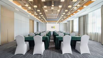 A conference room with a long table, white chairs, and a modern ceiling design.