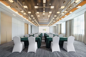 Una sala de conferències amb una taula llarga, cadires blanques i un disseny modern del sostre.
