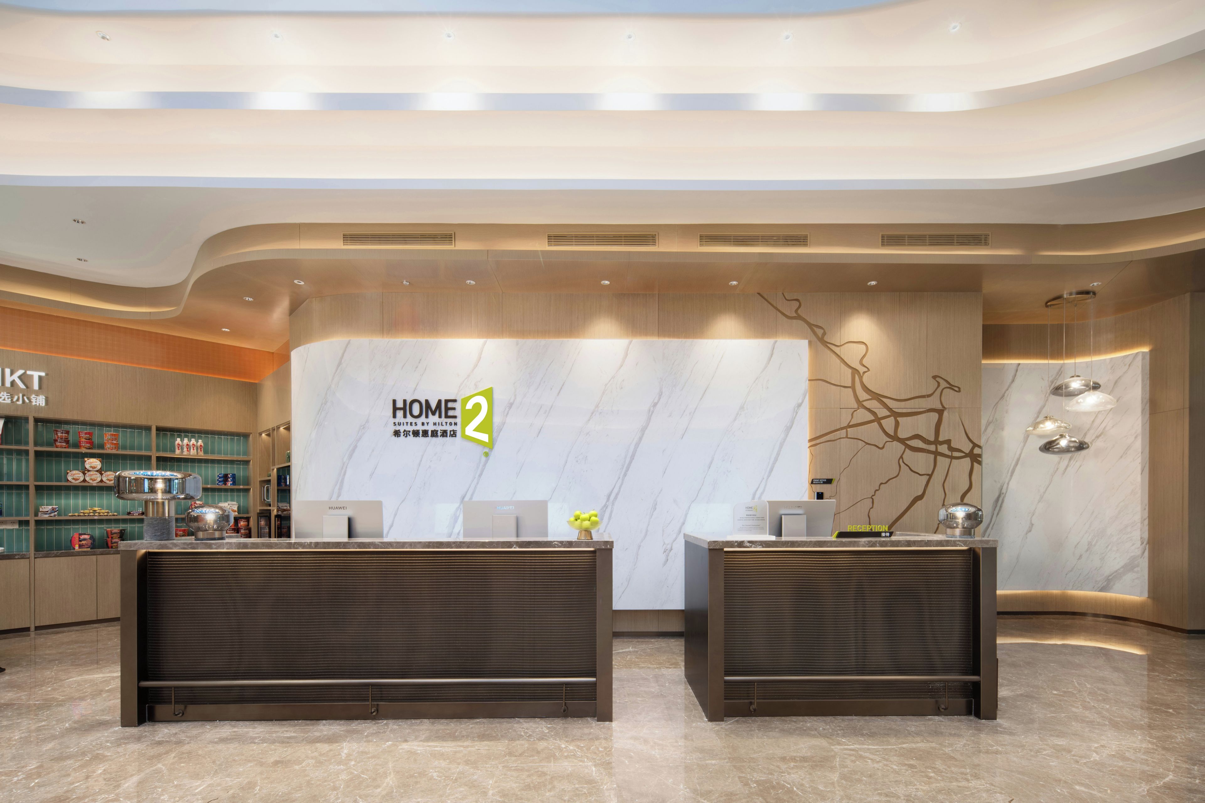 A hotel reception area with a marble wall, reception desk, and a decorative wall piece.