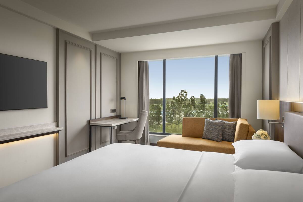 Ein modernes Hotelzimmer mit einem großen Bett, einem Schreibtisch, einer Couch und einem Fernseher.