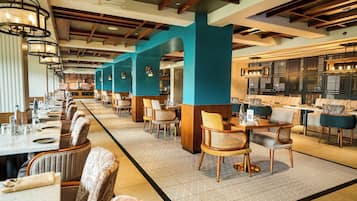A restaurant with long tables, chairs, and a bar area.