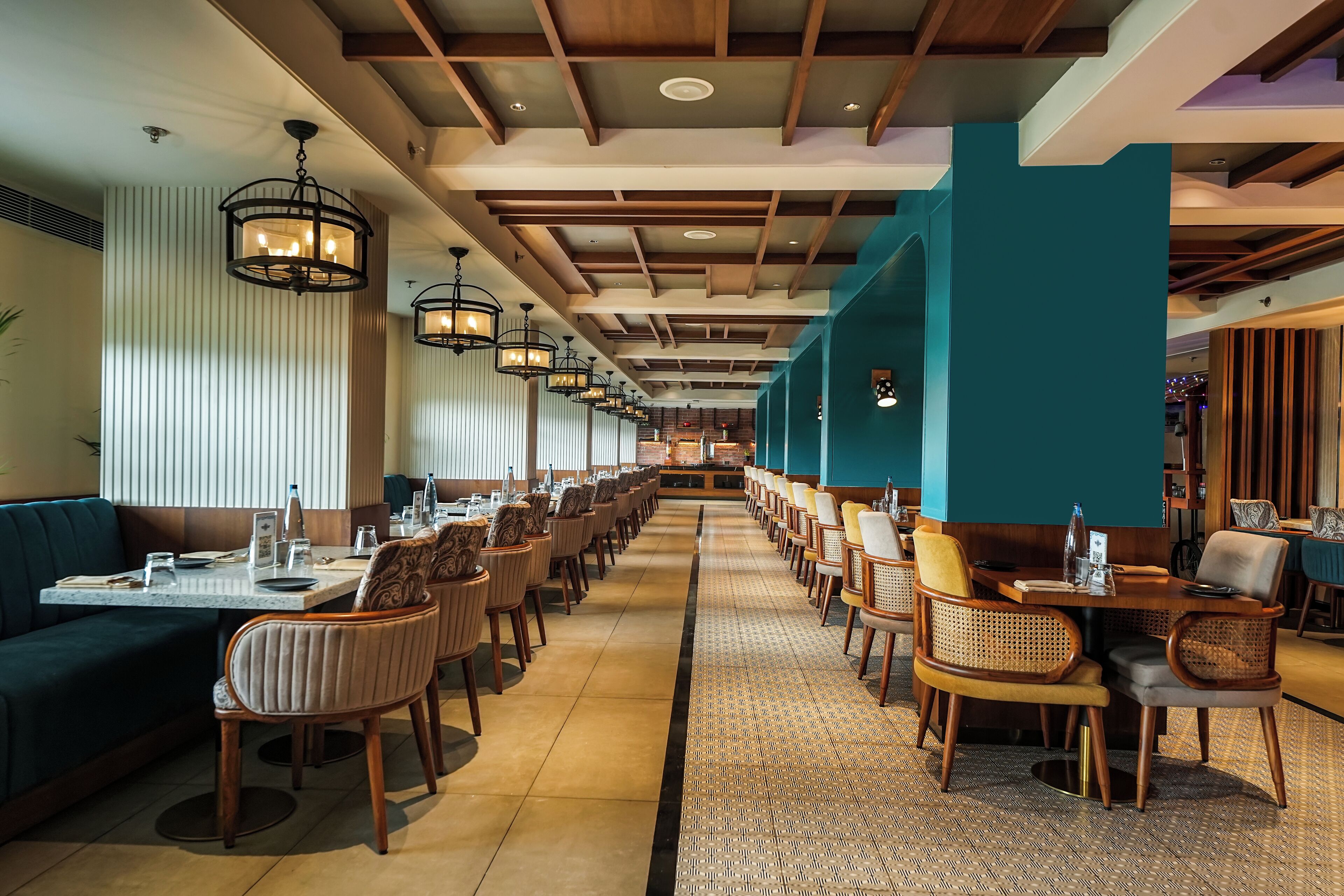 A long dining area with rows of tables and chairs, a central aisle, and a patterned floor.