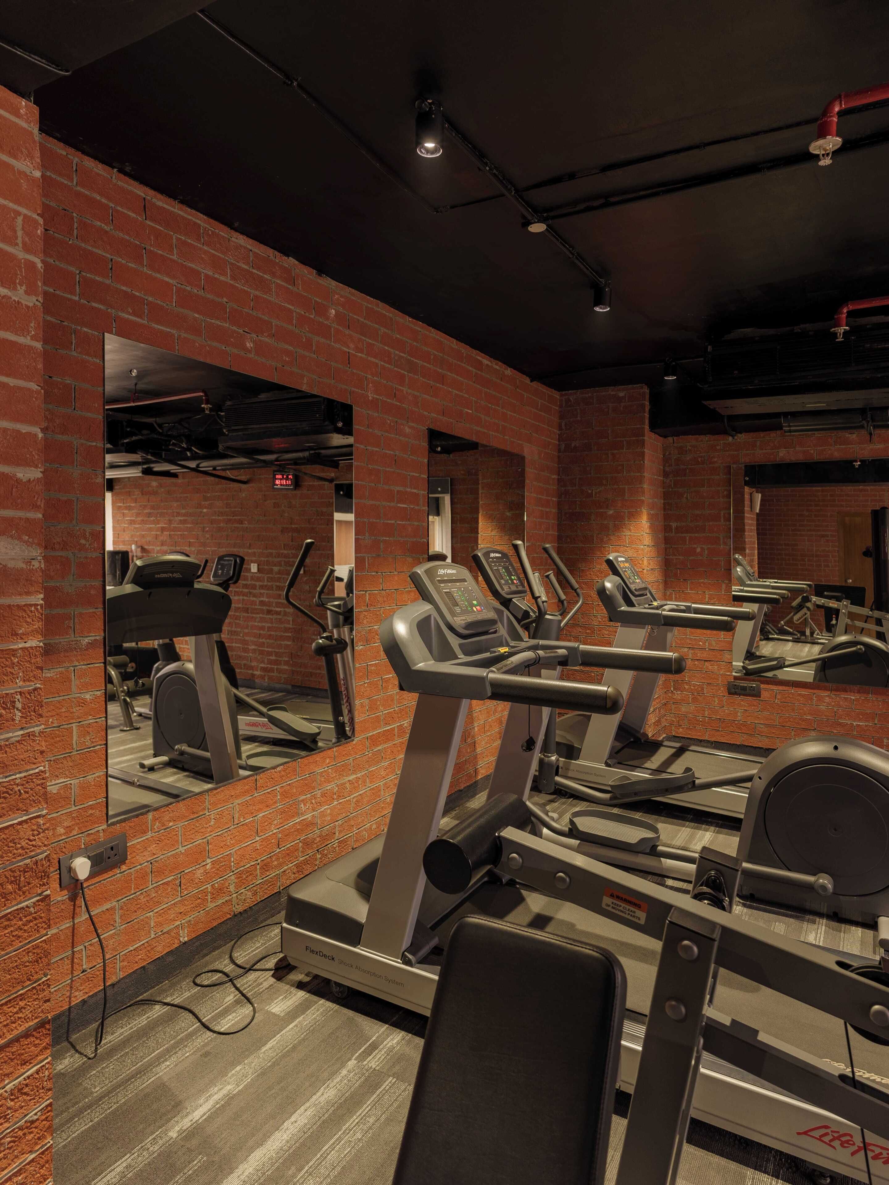 A gym with brick walls, treadmills, and a mirrored wall.