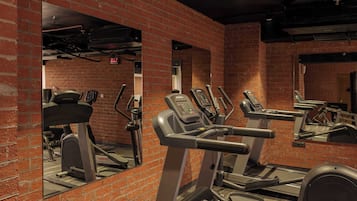A gym with brick walls, treadmills, and a mirrored wall.