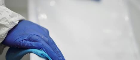 A person wearing blue gloves cleaning a white sink.