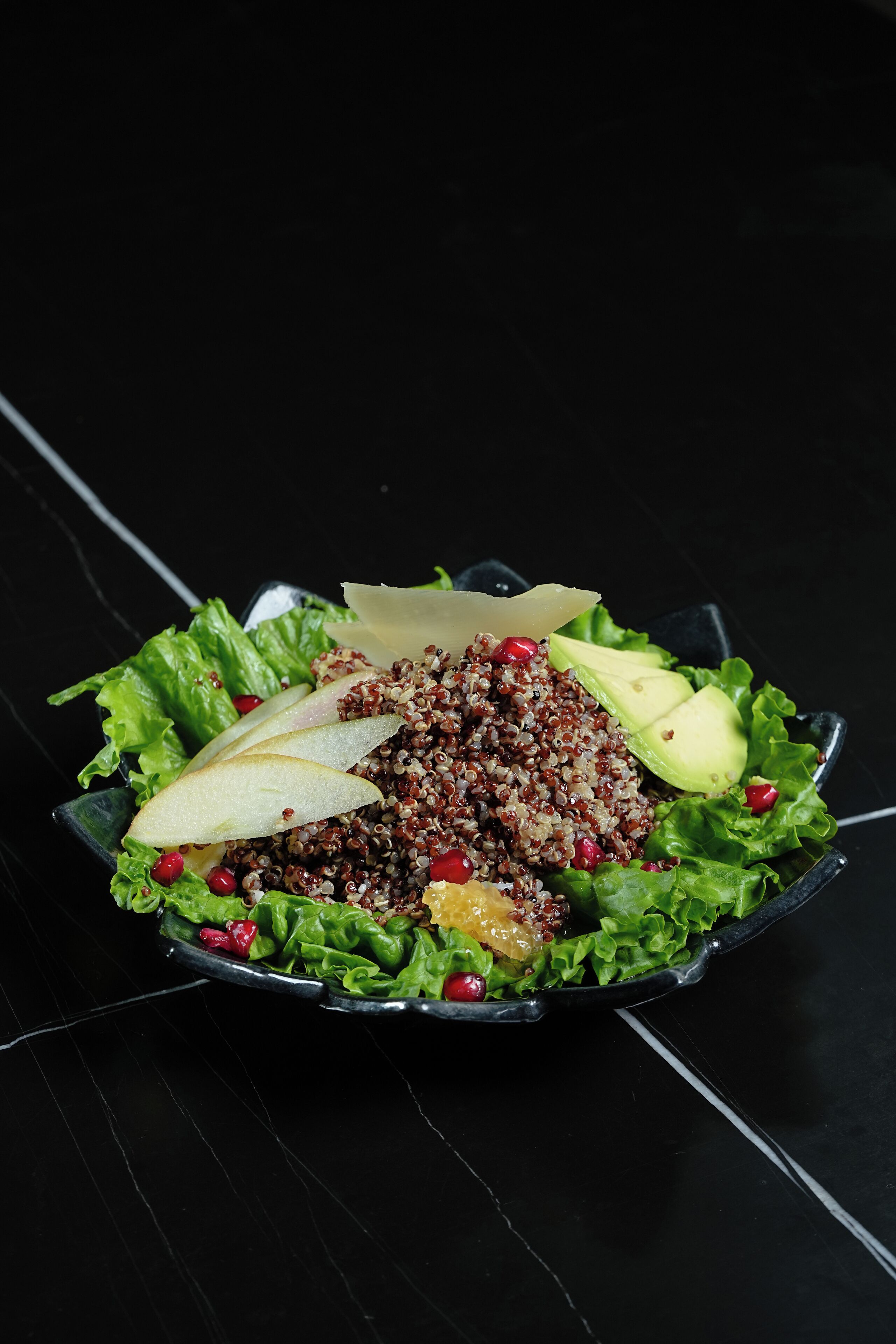 Ensalada con diversos ingredientes sobre un plato negro.