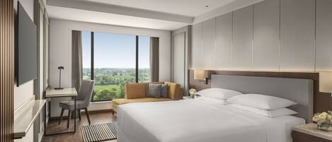 A modern hotel room with a large bed, a desk, and a view of the city.
