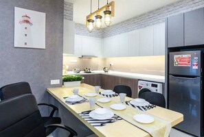 A modern kitchen with a dining area, a stainless steel refrigerator, and a mounted picture of a lighthouse.