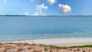 A coastal view with a clear sky, calm water, and a sandy beach with a metal railing. - Bayfront Riviera Retreat with Pool and HVAC! (San Diego)