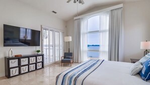 A modern hotel room with a large bed, a TV, a desk, and a view of the sea. - Bayfront Riviera Retreat with Pool and HVAC! (San Diego)