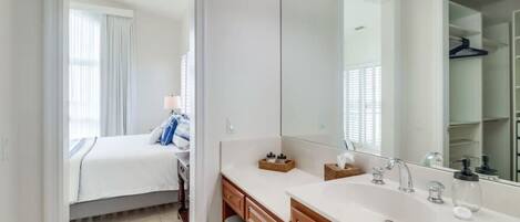 Une salle de bain moderne dotée d’un grand miroir, de deux vasques et d’un dressing.