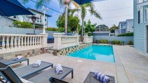 A backyard with a swimming pool, lounge chairs, and a covered patio area. - Bayfront Riviera Retreat with Pool and HVAC! (San Diego)