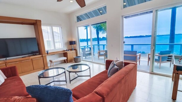 A spacious living area with a large sofa, two glass coffee tables, a TV, and a balcony with a view of the sea. - Bayfront Riviera Retreat with Pool and HVAC! (San Diego)