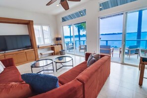 A spacious living area with a large sofa, two glass coffee tables, a TV, and a balcony with a view of the sea. - Bayfront Riviera Retreat with Pool and HVAC! (San Diego)