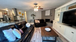 A modern living room with a black leather sofa, a wooden coffee table, and a flat-screen TV. - Nearby North Dallas - Grandscapes (The Colony)