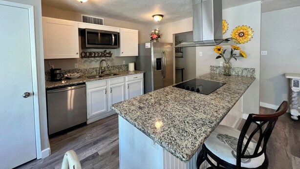 A modern kitchen with granite countertops, stainless steel appliances, and a built-in microwave. - Nearby North Dallas - Grandscapes (The Colony)