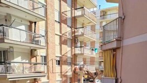A multi-story residential building with balconies, a gated entrance, and a small garden area. - Fantastico Apartamento LA Pineda a 50 Metros de la Playa 2 Habitaciones (Platja de la Pineda)