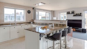 Uma cozinha moderna com uma ilha grande, banquetas e uma área de jantar com televisão.