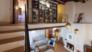 A spacious living area with a high ceiling, a staircase, a bookshelf, a sofa, and a fireplace. - Tuscany Siena Florence Chianti Swimming pool Felsina Brancaia tenuta Arceno. (Toscana)