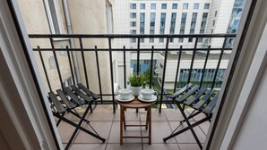 A balcony with a small table, two chairs, and a potted plant. - Stylish Apartment in the Center | Balcony and View of the City (Warszawa)