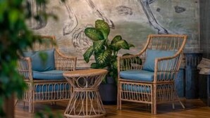 Ein Zimmer mit Korbmöbeln, einer großen Wandmalerei und einem Blumentopf.