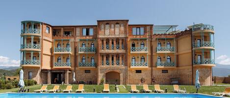 A multi-story hotel with a swimming pool, multiple balconies, and a central courtyard.