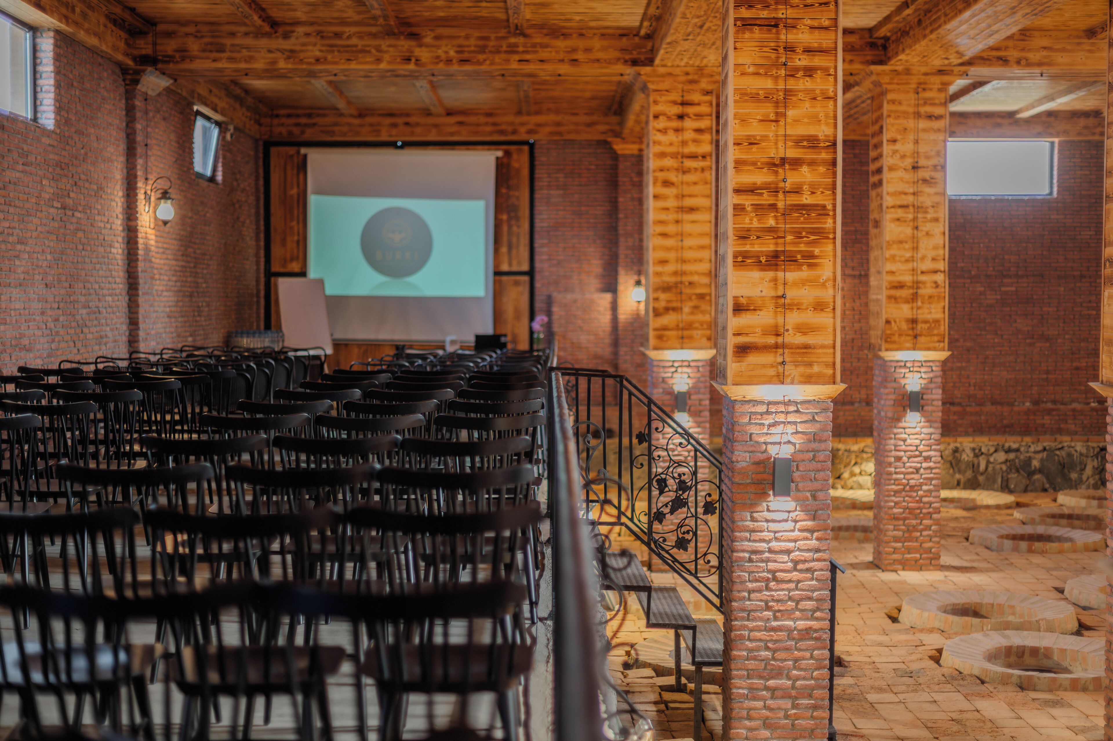 An indoor venue with rows of chairs, a projector screen, and brick walls.