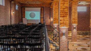 An indoor venue with rows of chairs, a projector screen, and brick walls.