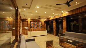 A modern lobby with a reception desk, seating area, and a ceiling fan. - Hotel Sparkle Inn (Udaipur)