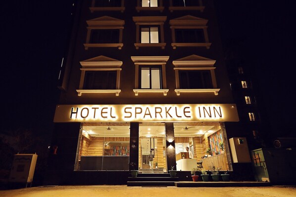 The exterior of Hotel Sparkle Inn at night with illuminated signage.