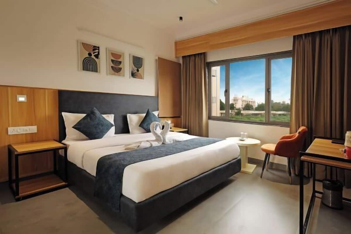 Habitación de hotel con una cama grande, una mesita, una silla y ventana con vistas.