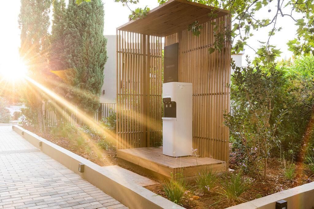Une structure extérieure moderne dotée d’un système de climatisation intégré, entourée de verdure et bordée d’un chemin pavé.