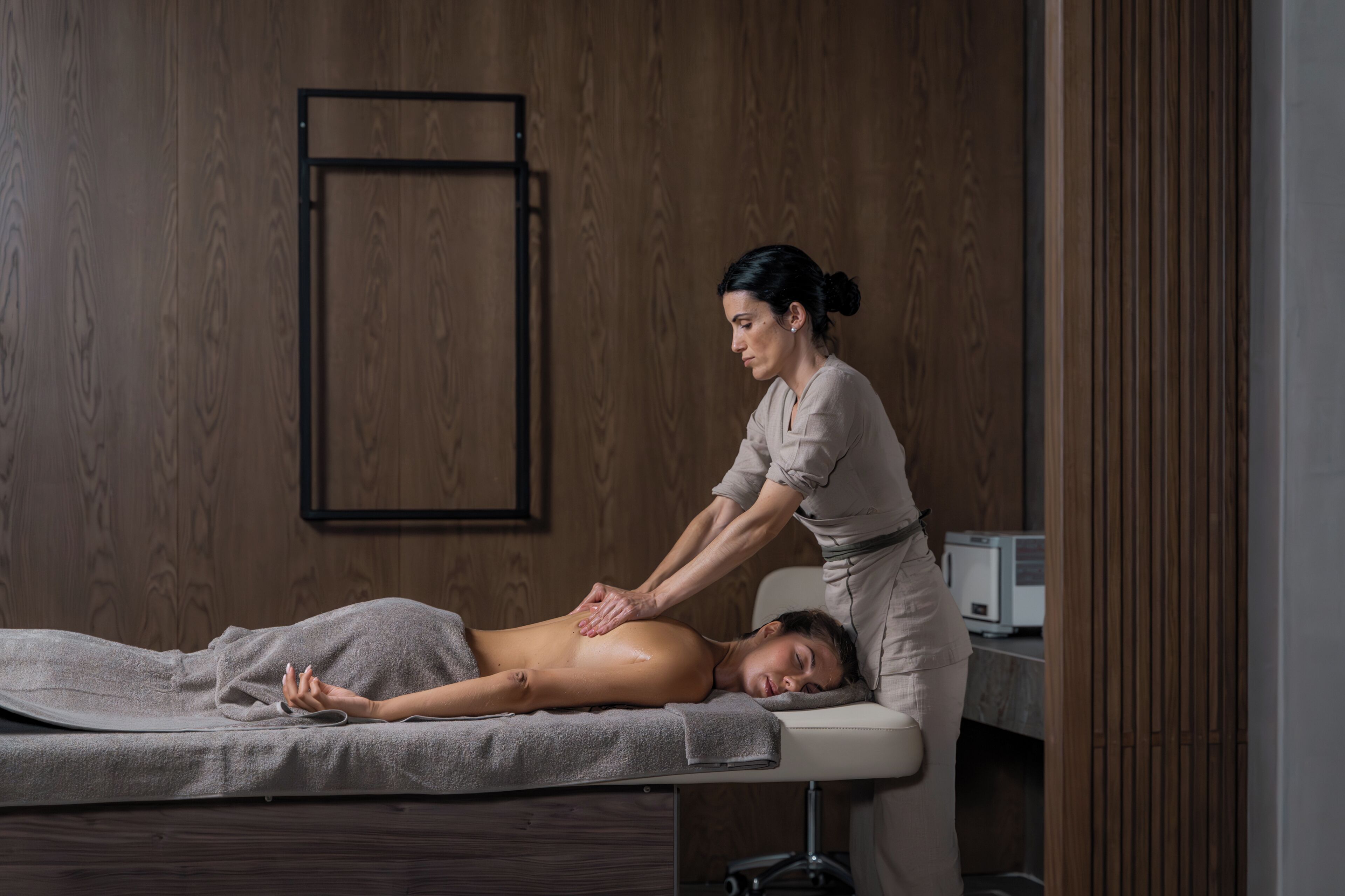 A massage therapy session in a room with wooden paneling and a massage table.