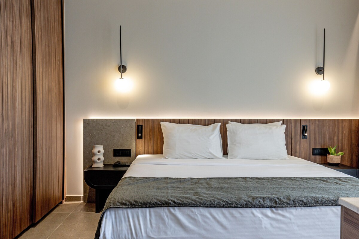 Ein modernes Hotelzimmer mit einem großen Bett, einem Holzkopfteil, Nachttischen und Wandleuchten.