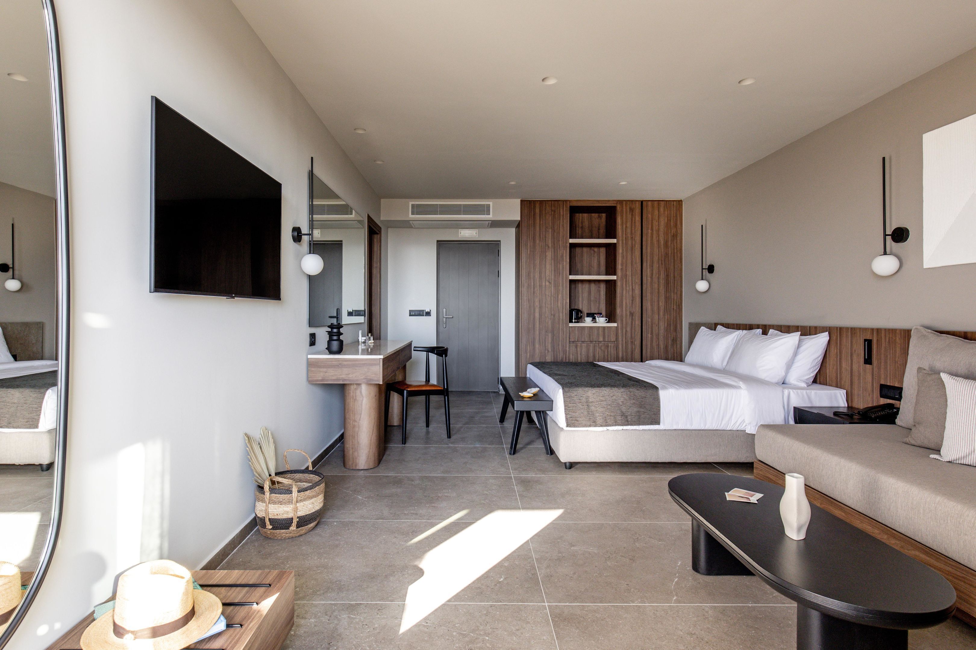 Una habitación de hotel moderna con cama, sofá, escritorio y un espejo grande.