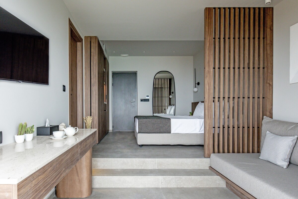 Ein modernes Hotelzimmer mit Bett, Sofa, Schreibtisch und Fernseher.