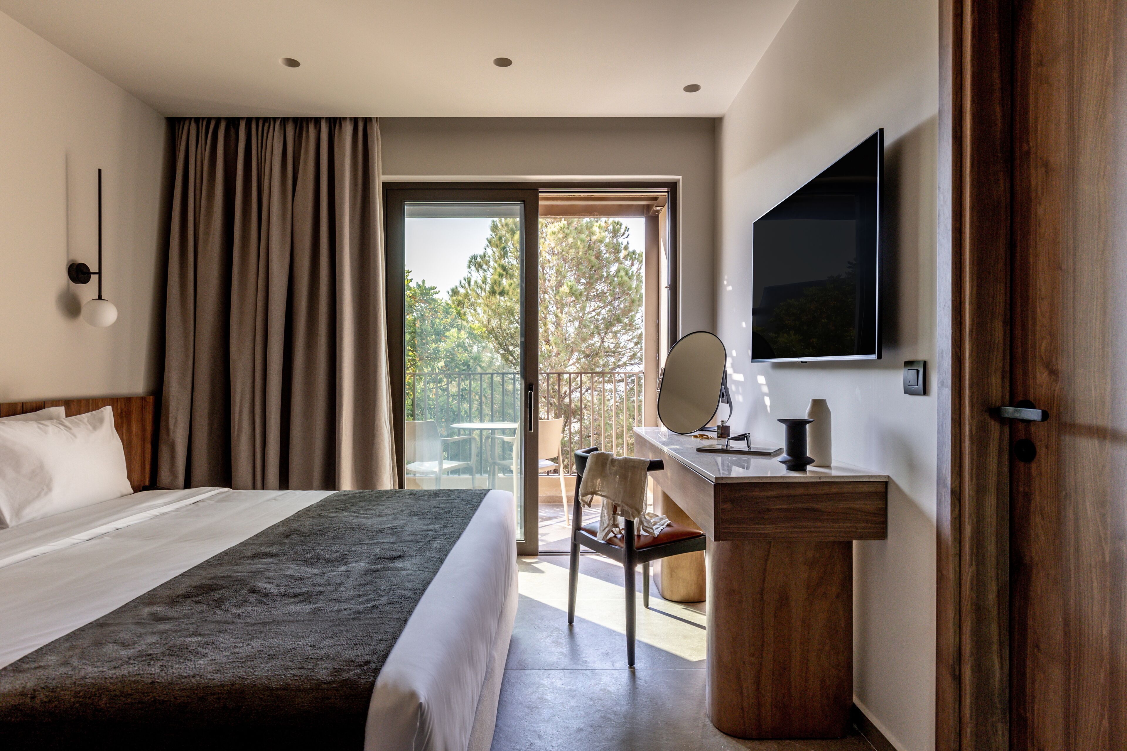 Una habitación de hotel moderna con una cama grande, un escritorio con espejo y un televisor.