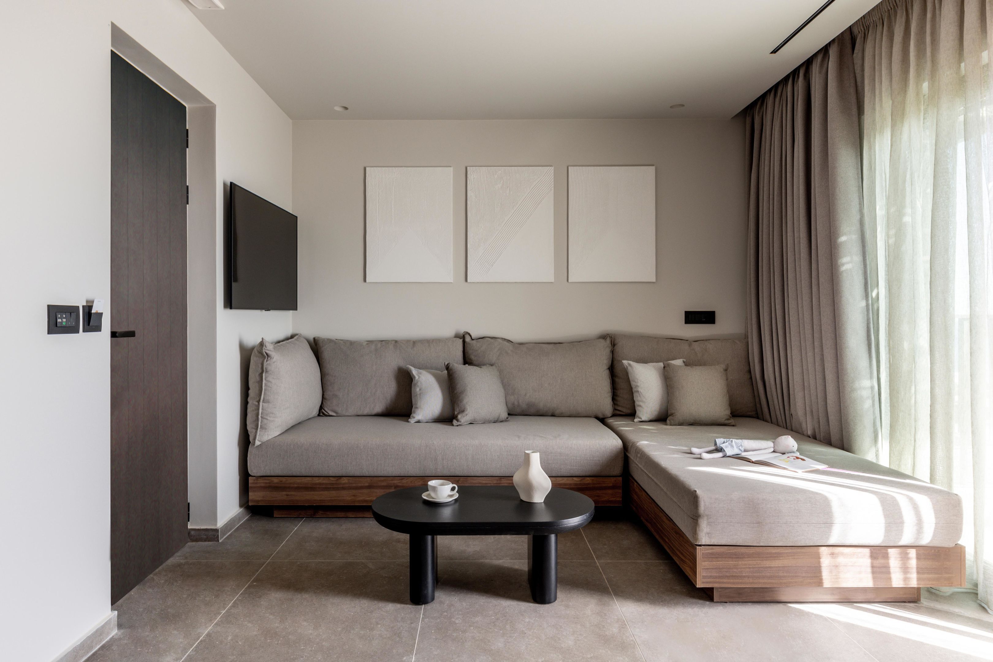 Un salon moderne avec un canapé, une table basse et un téléviseur à écran plat fixé au mur.