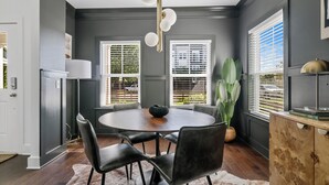 A dining area with a round table, black chairs, a white rug, and a wooden cabinet.
