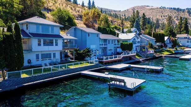 A waterfront property with multiple houses, clear water, and a dock. - 3Bed, 2.5Bath Waterfront Home with Boat Lift! (Chelan)