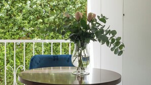 A balcony with a round table, a vase with flowers, and blue chairs. - Residenza Amalphia (Amalfi)