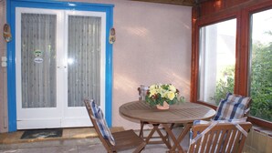 A patio with a round wooden table, two wooden chairs, and a flower arrangement.