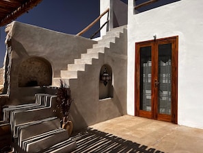 Steps lead up to a door with glass panels, flanked by arched niches and a potted plant.