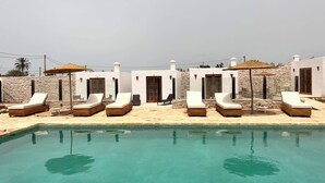 A pool area with lounge chairs and a stone wall backdrop.