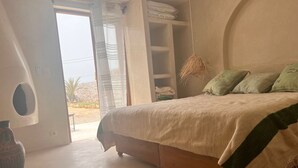A bedroom with a bed, a wardrobe, and a large window.
