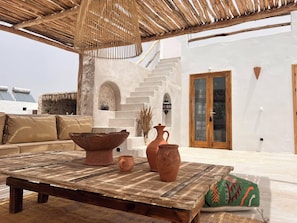Relax in this serene outdoor seating area with a rustic table, comfortable cushions, and a charming arched doorway.