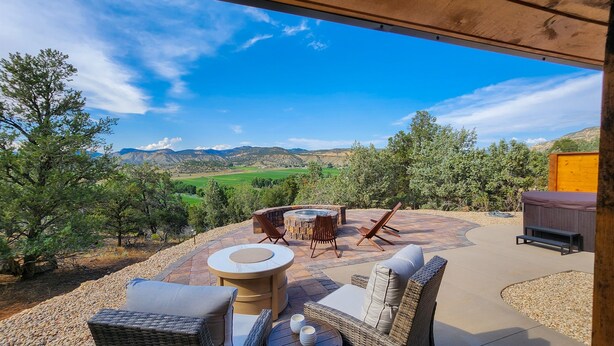 Un patio al aire libre con mobiliario de mimbre, una mesa redonda y un jacuzzi.