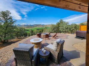 Eine Terrasse im Freien mit Korbmöbeln, einem runden Tisch und einem Whirlpool.
