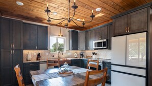Una cocina moderna con armarios oscuros, una mesa de comedor de madera y un microondas integrado.