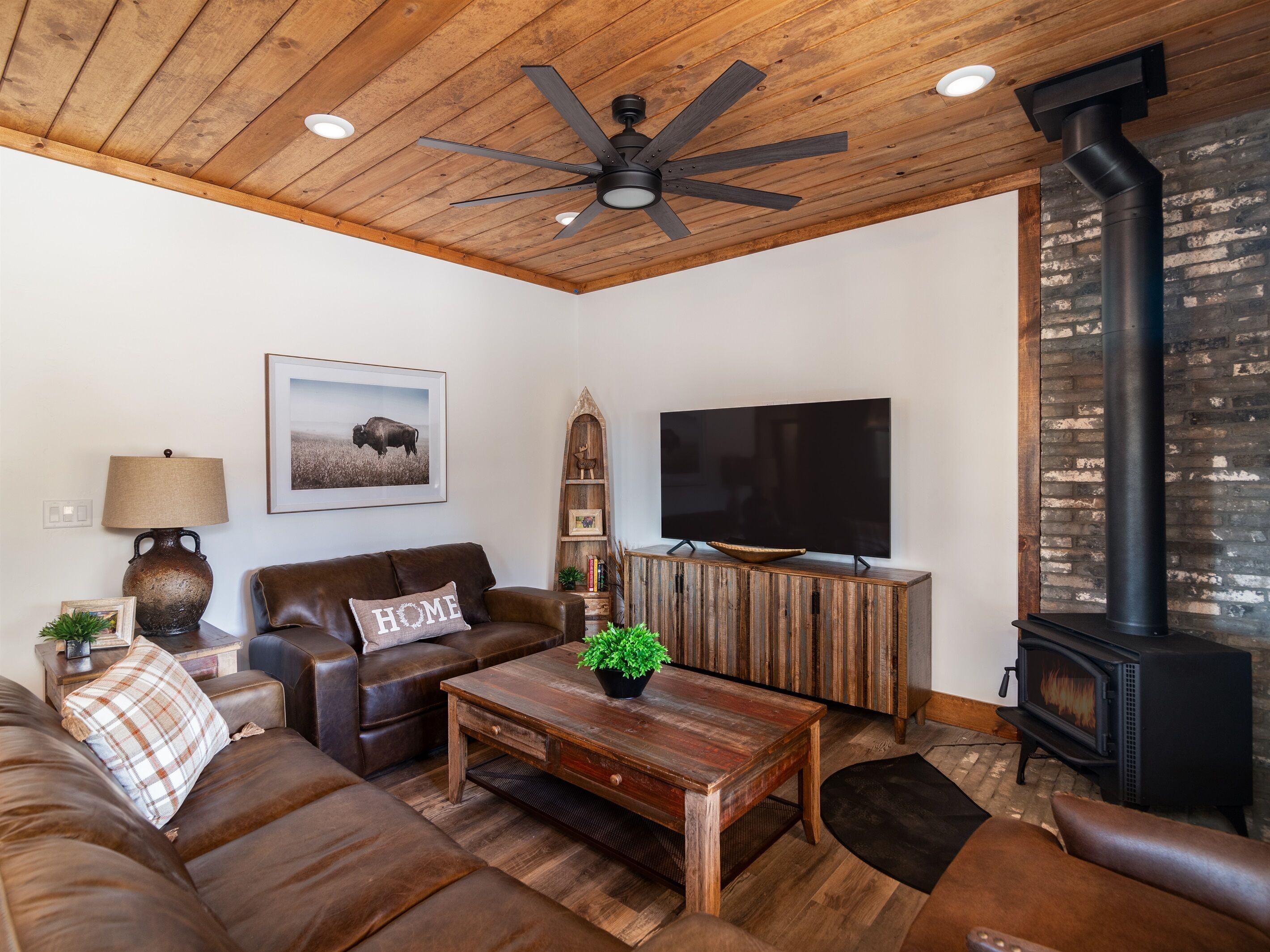 A cozy living room with a leather couch, a wooden coffee table, a television, and a fireplace.
